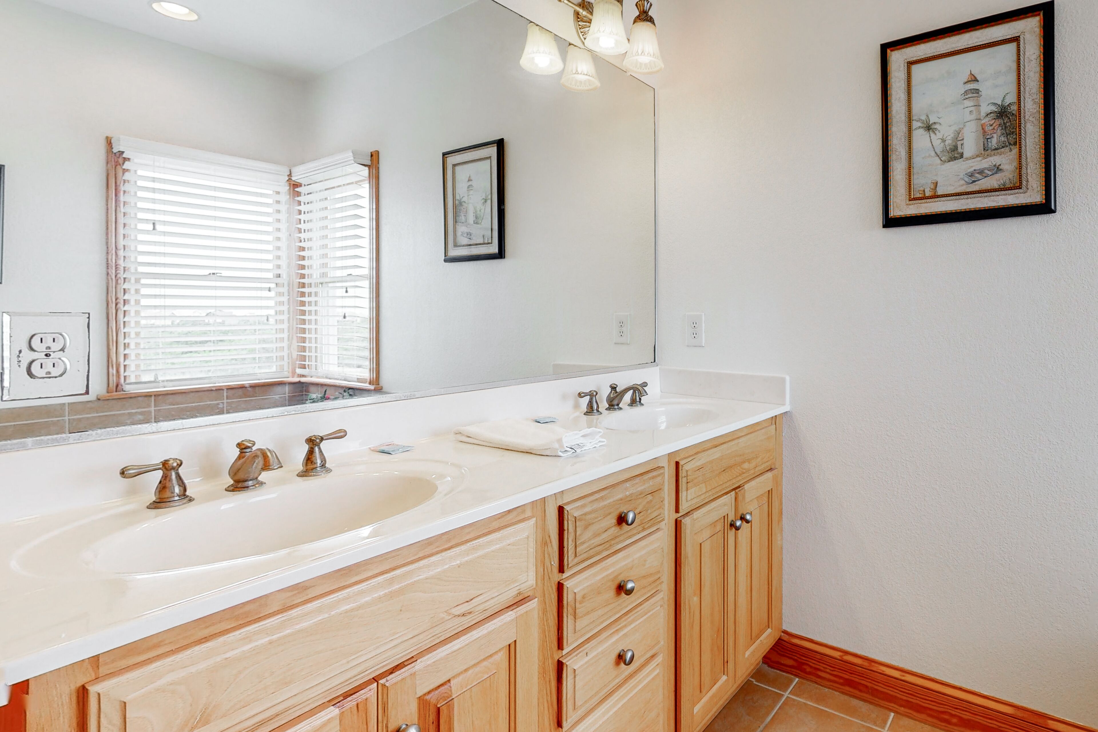 Une salle de bain avec un grand miroir, deux lavabos, des meubles en bois et un tableau encadré au mur.