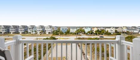 A balcony with white railings and two Adirondack chairs.