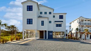 A multi-story hotel with a covered entrance and outdoor seating area. - Take Me A-Wave: Water-view, pool, foosball, grill, & two W/Ds (Ocean Isle Beach)