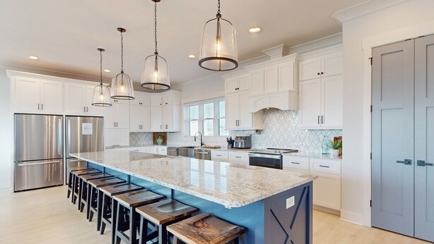 A modern kitchen with a large island, stainless steel appliances, and pendant lighting. - Take Me A-Wave: Water-view, pool, foosball, grill, & two W/Ds (Ocean Isle Beach)