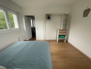 Un dormitorio con cama, armario, espejo y ventana.