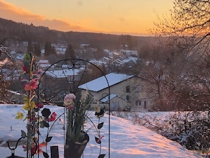 Un paisaje nevado con un arreglo floral de metal en primer plano y casas al fondo.