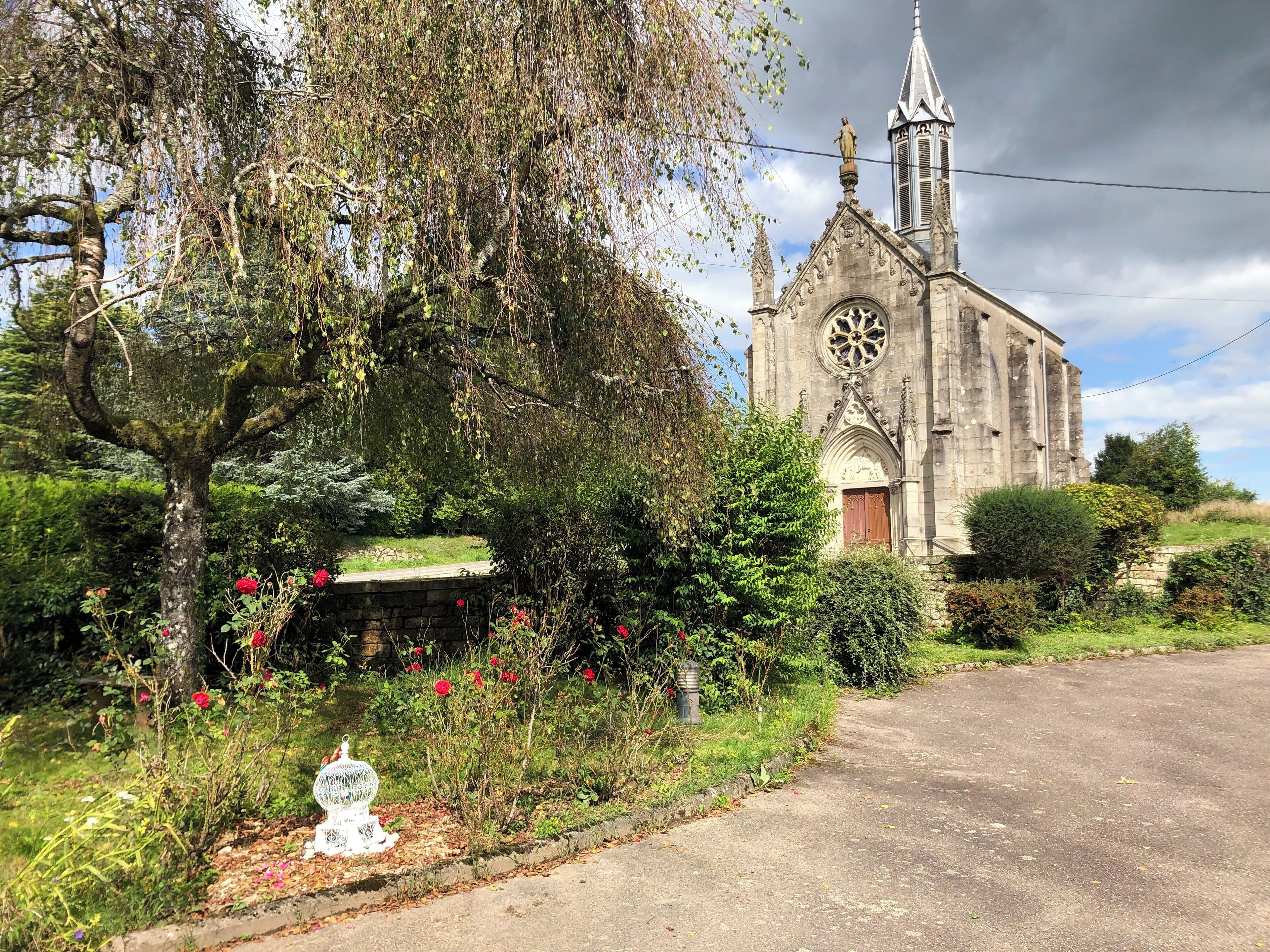 Een kerk met een hoge spits en een groot rond raam.