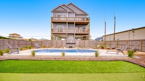 A two-story house with a backyard swimming pool, surrounded by a wooden fence. - Ocean-view beach home - private hot tub, elevator, cook's kitchen - dog-friendly (North Topsail Beach)