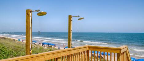 A wooden deck with a view of the beach and ocean.