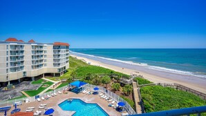 Un hotel con piscina, vista a la playa y un paseo marítimo.