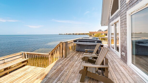 A wooden deck with a hot tub and chairs overlooking a body of water. - Waterfront  house with pool, W/D, private hot tub, & AC (Frisco)