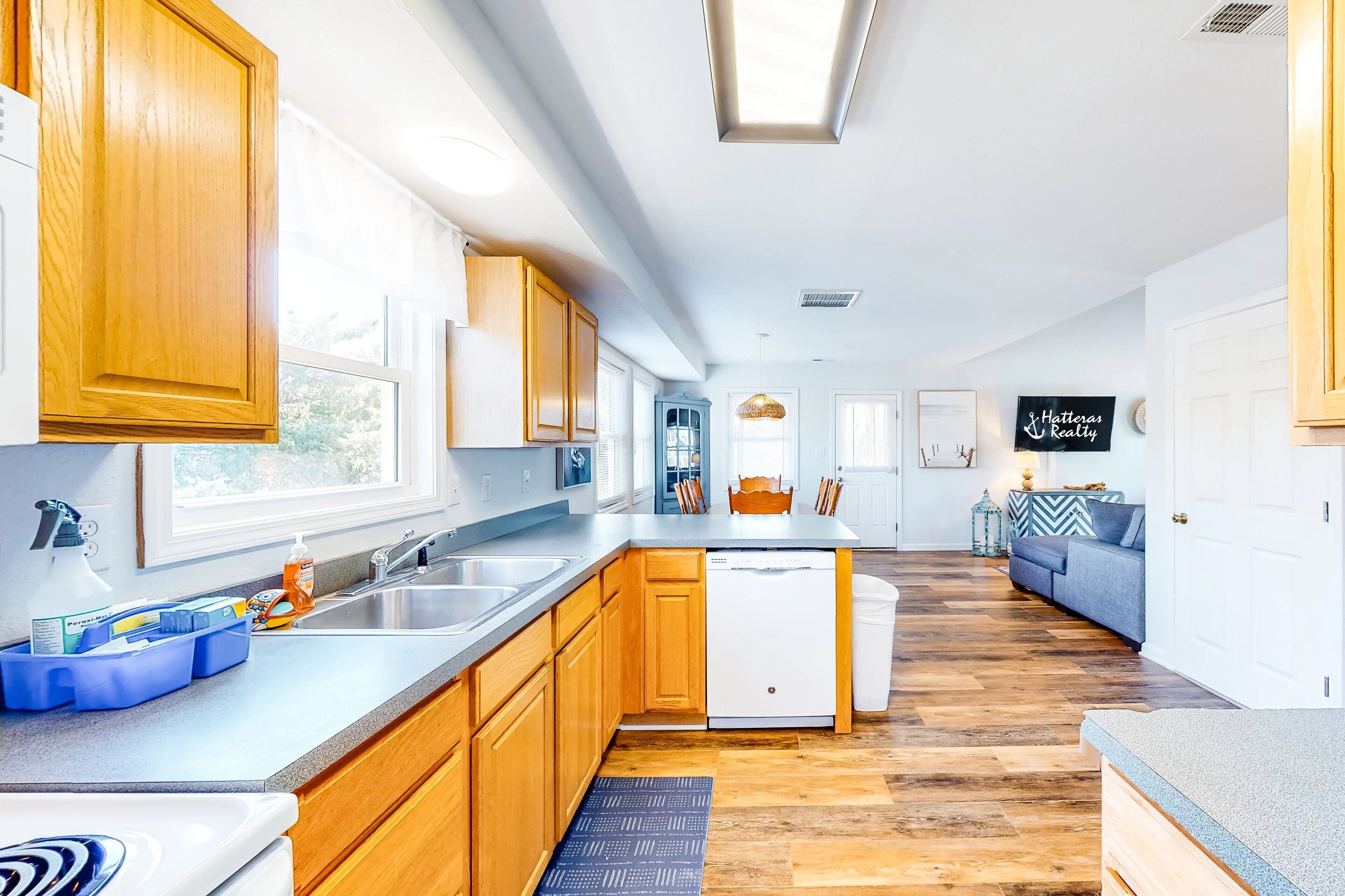 A modern kitchen with wooden cabinets, a built-in dishwasher, and a large window.