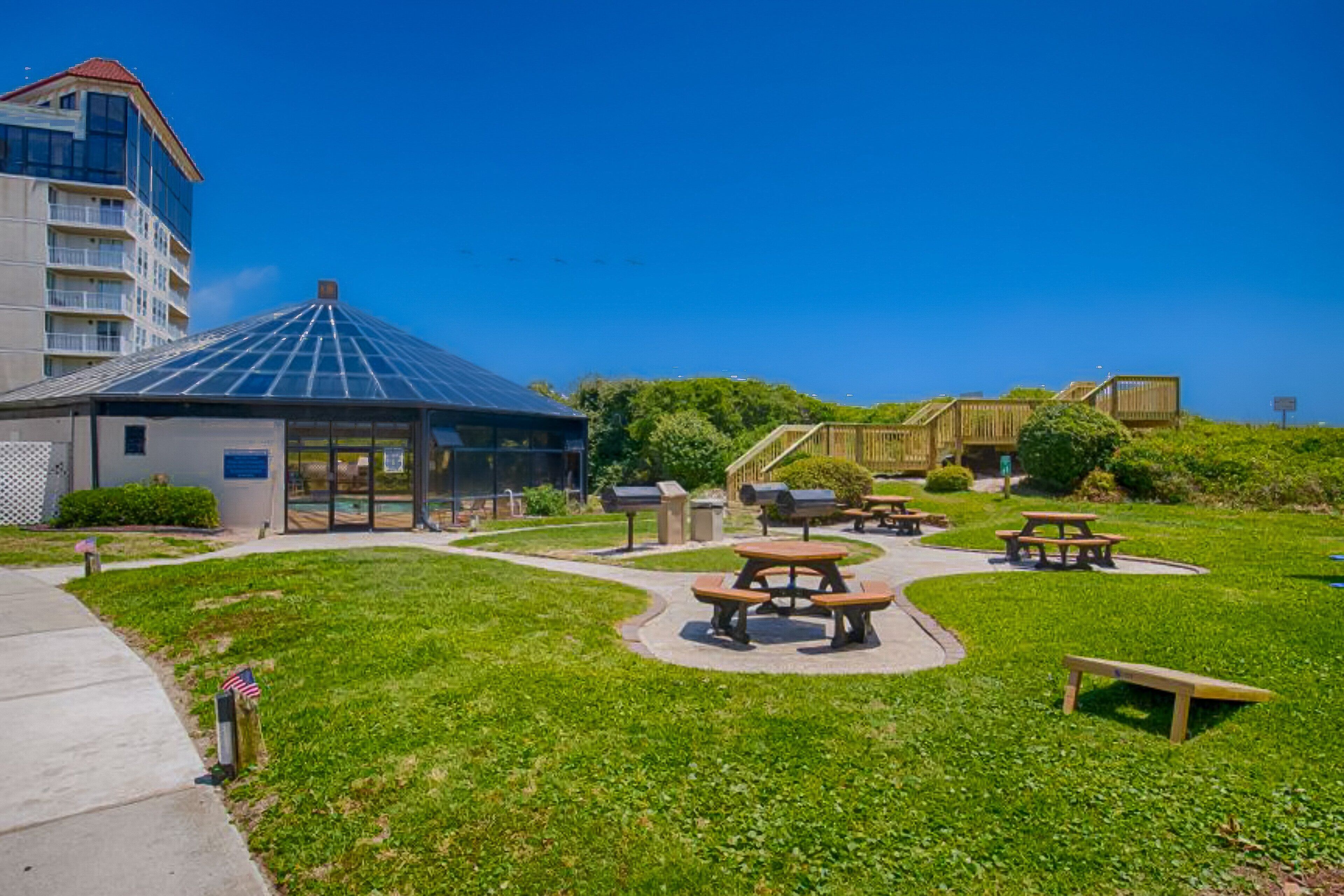 Ett grönområde med picknickbord och en överbyggd paviljong.