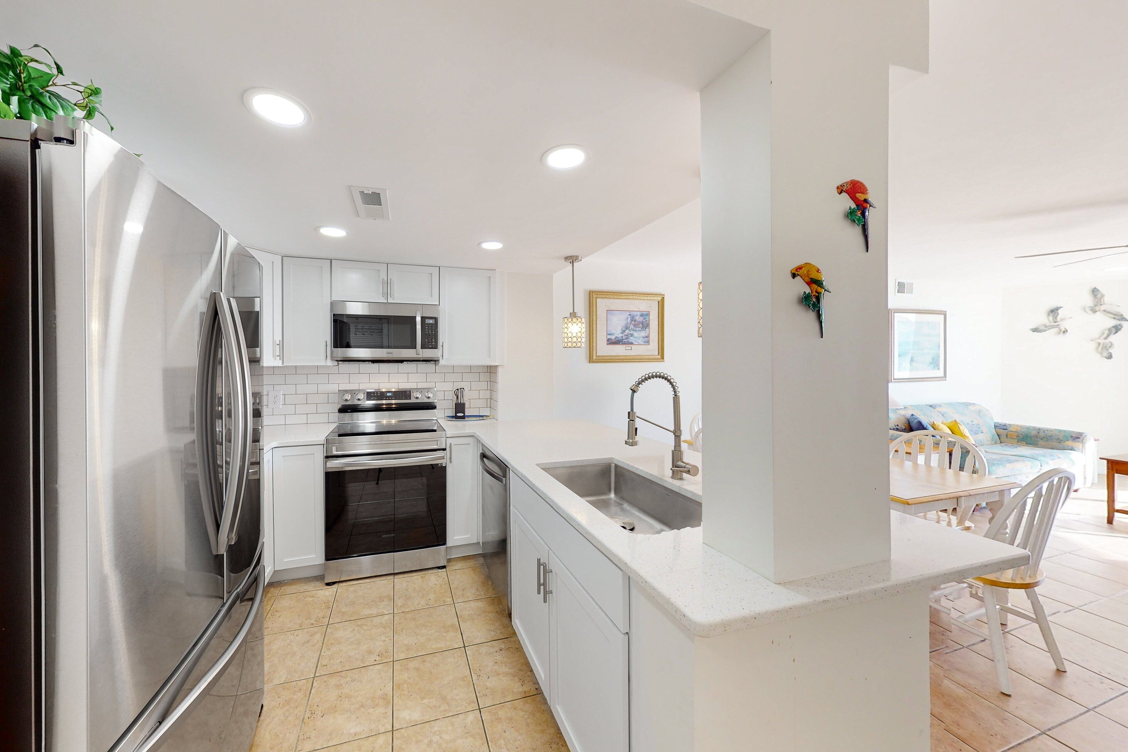 A modern kitchen with stainless steel appliances, white cabinetry, and a central island with a sink.