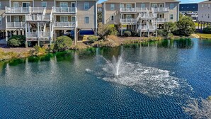 A waterfront property with multi-story buildings, outdoor decks, and a pond.