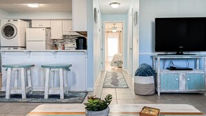 A modern kitchen with appliances, a dining area with a table and chairs, and a living room with a television.