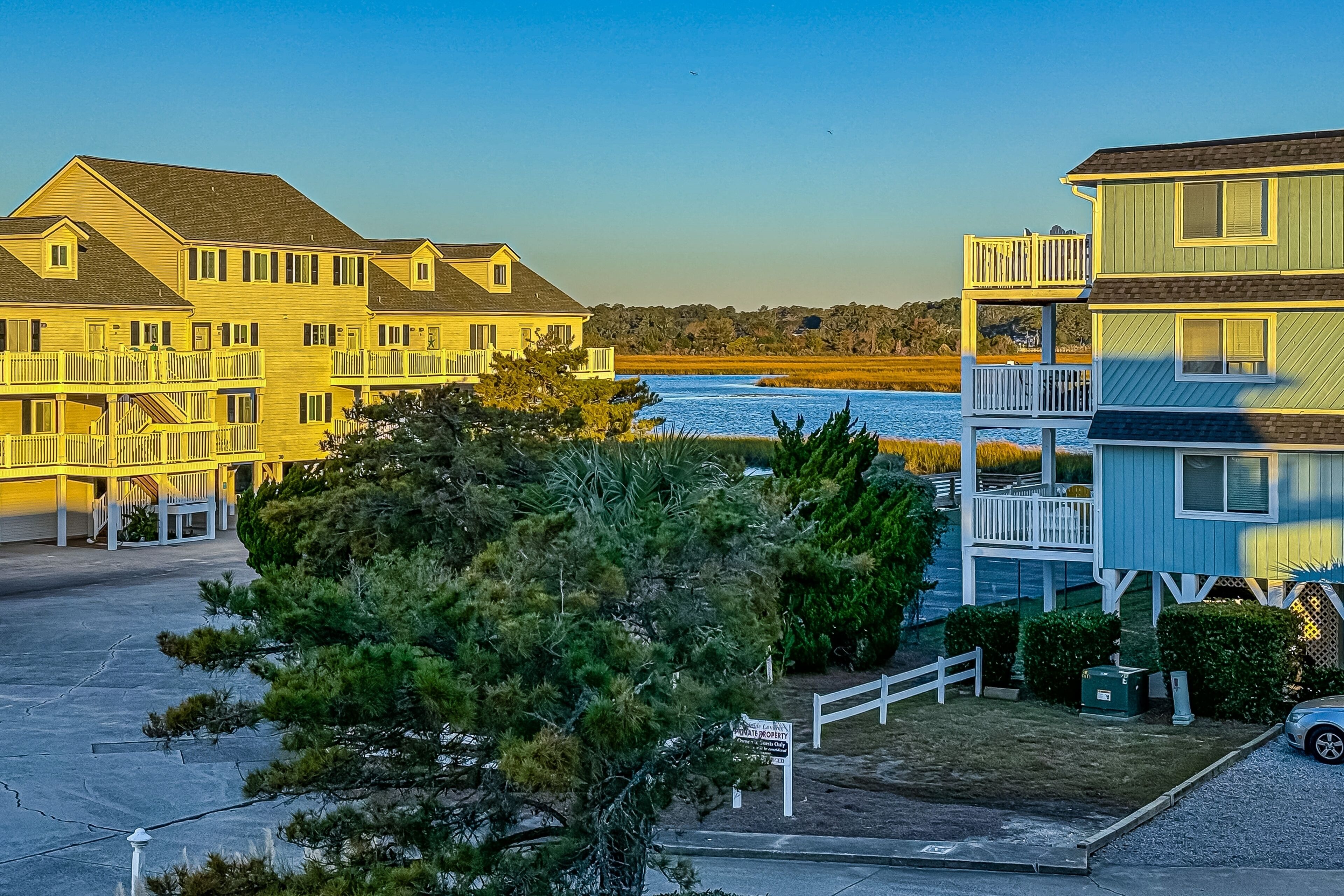 A coastal residential area with multi-story buildings, a visible beach, and a clear sky.