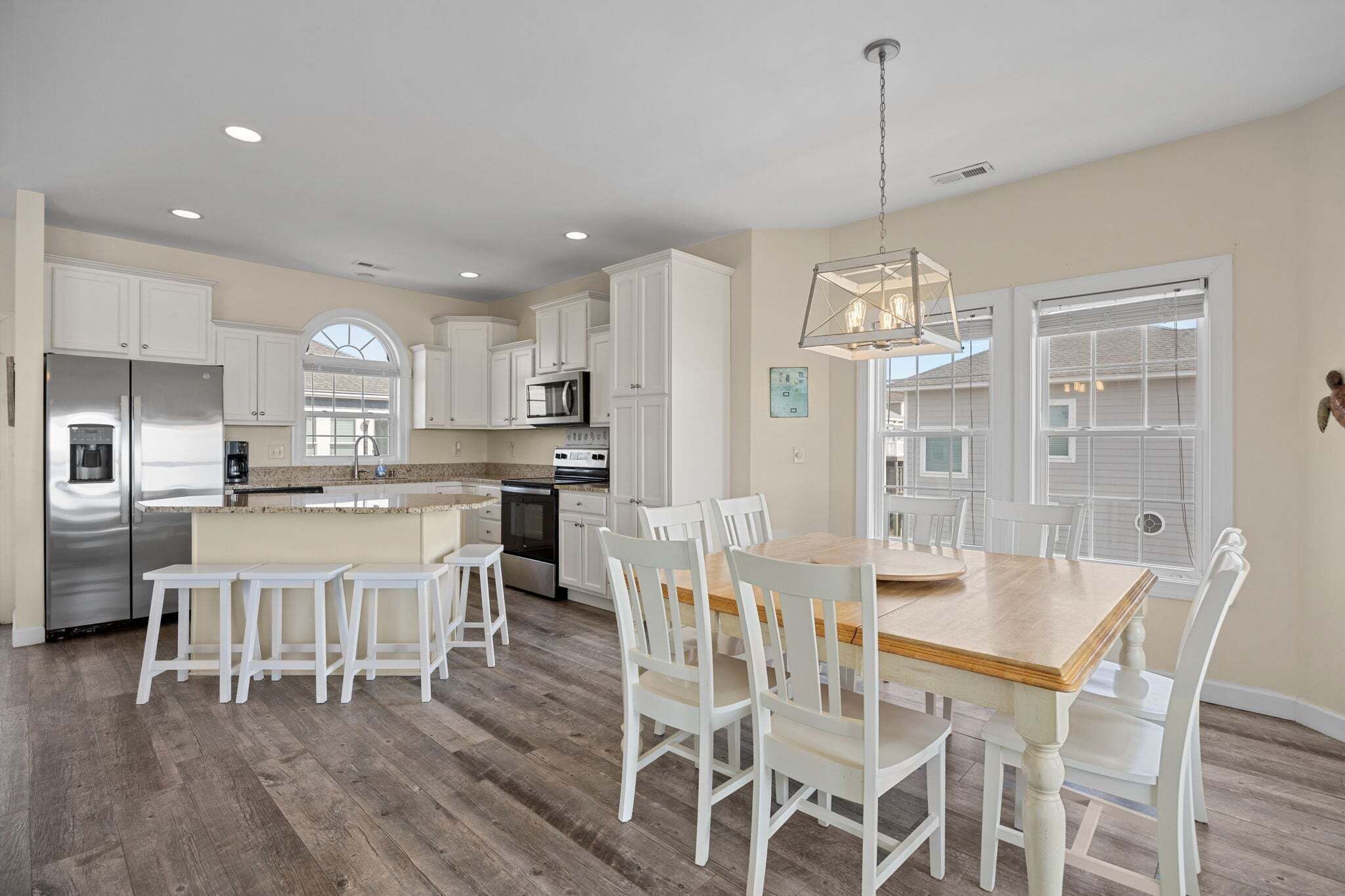 A spacious kitchen with white cabinetry, a wooden dining table, and a large island.