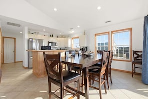 A spacious kitchen with a central island, white cabinetry, and large windows.