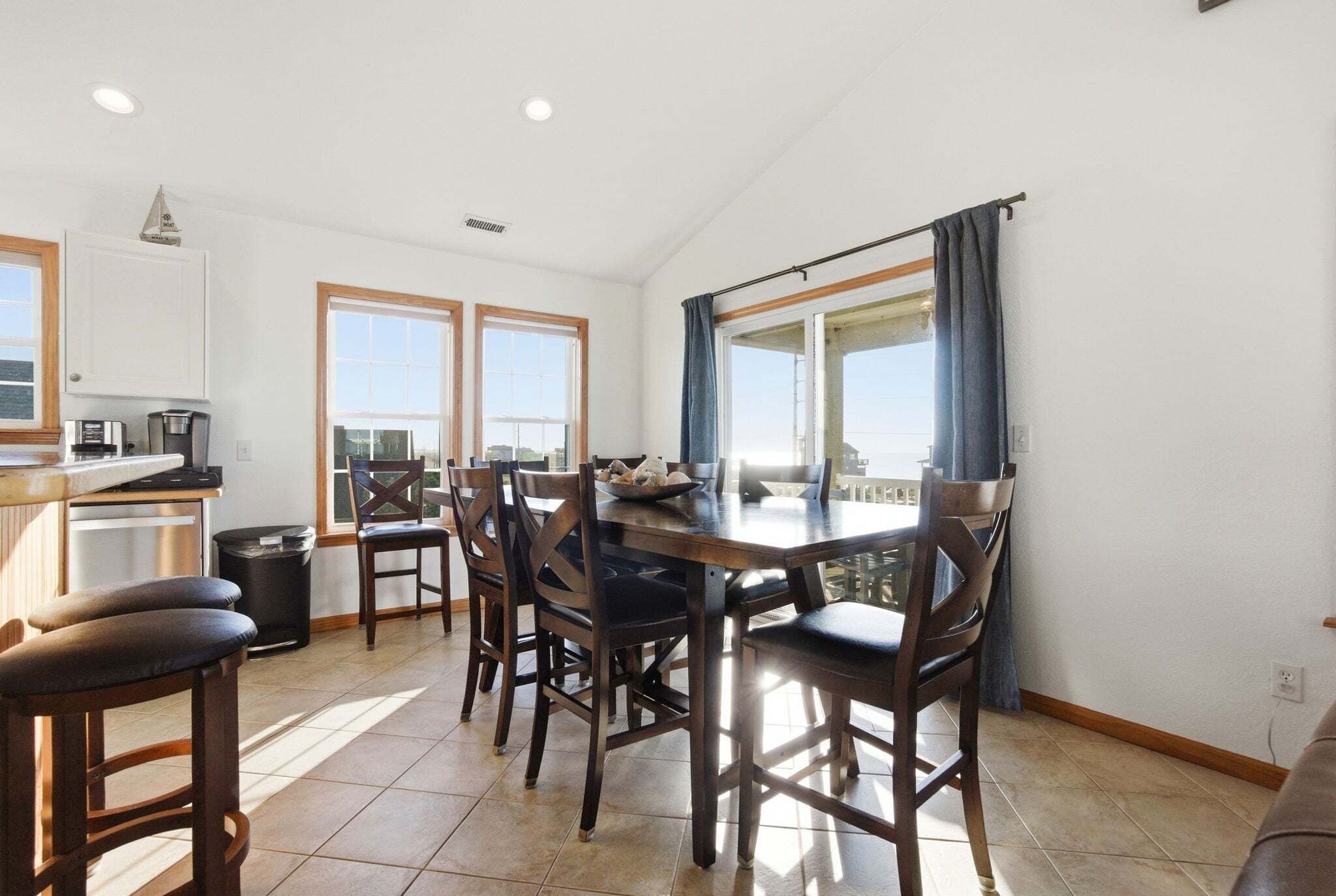 A dining area with a table, chairs, and a view of the sky through a window.