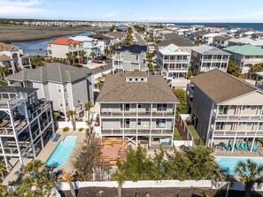 Zona residencial costera con varios edificios de dos pisos, piscina y vista a la playa.