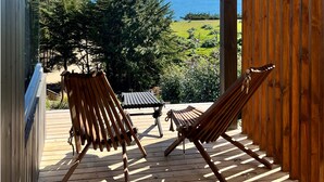 A wooden deck with two lounge chairs facing a scenic view of the ocean and greenery. - Chackra Centinela  (Navidad)