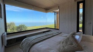 A bedroom with a large window offering a view of the sea and greenery. - Chackra Centinela  (Navidad)