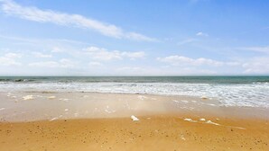 Une plage avec un ciel dégagé et une mer calme.