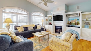 A living room with a sofa, armchair, coffee table, fireplace, and decorative shelves. - Grams Getaway: Private pool, deck, & patio - walk to the beach (Ocean Isle Beach)