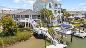 A waterfront property with a dock, a boat, and a large house with multiple decks and a tower. - Fore Buoys: Canalfront, dock, close to beach! (Ocean Isle Beach)