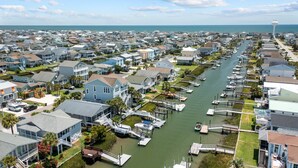 A marina with boats docked along a waterway surrounded by residential houses. - Fore Buoys: Canalfront, dock, close to beach! (Ocean Isle Beach)