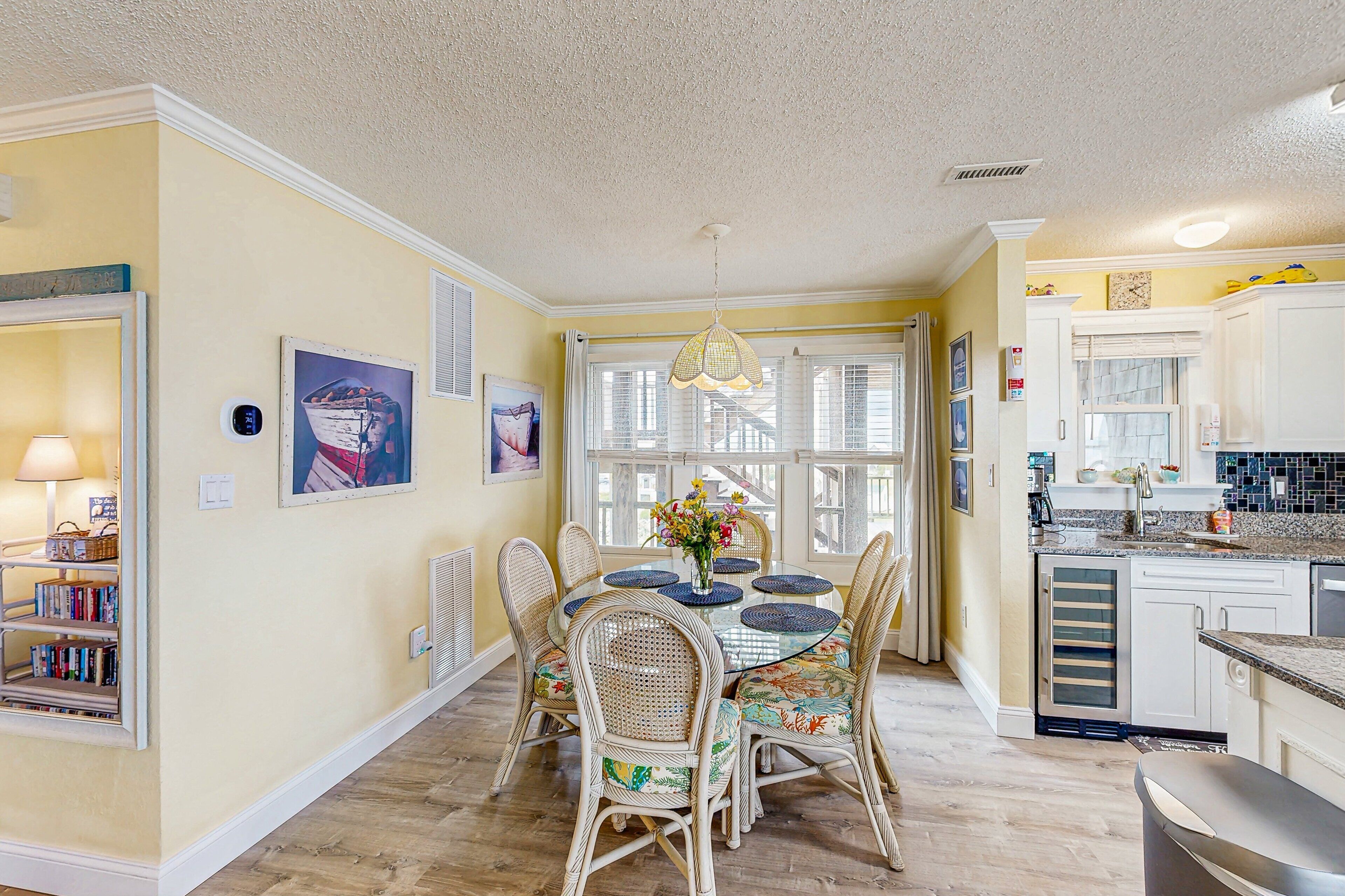 A dining area with wicker chairs, a round table, and a chandelier.