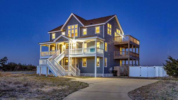 A two-story house with a balcony on the second floor, a staircase leading to the second floor, and a covered front porch. - Dog-friendly oceanfront home with private outdoor pool, hot tub & central AC (Waves)