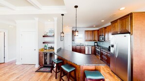 A spacious kitchen with wooden cabinets, stainless steel appliances, and a bar area with stools. - Beautiful dog-friendly ocean view home with hot tub, lovely balcony, W/D & AC (North Topsail Beach)