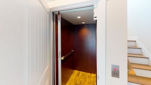 A modern interior with a wooden staircase, a door leading to a room with a dark wooden floor, and a light switch on the wall. - Beautiful dog-friendly ocean view home with hot tub, lovely balcony, W/D & AC (North Topsail Beach)