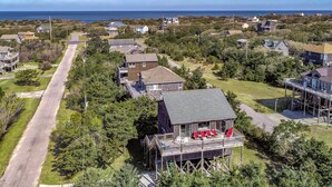 A coastal residential area with houses, a prominent house with a deck and red chairs, and a road leading to the sea. - Beach home near the ocean w/sunny deck, washer/dryer, and central A/C (Frisco)