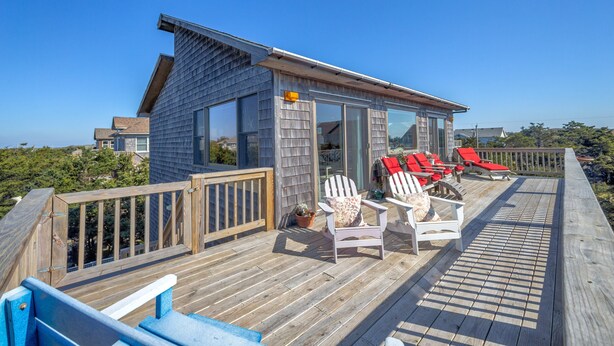 A wooden deck with red lounge chairs and a small building with large windows. - Beach home near the ocean w/sunny deck, washer/dryer, and central A/C (Frisco)