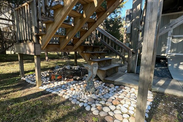 A wooden play structure with steps and a climbing area, surrounded by a garden with a stone pathway.