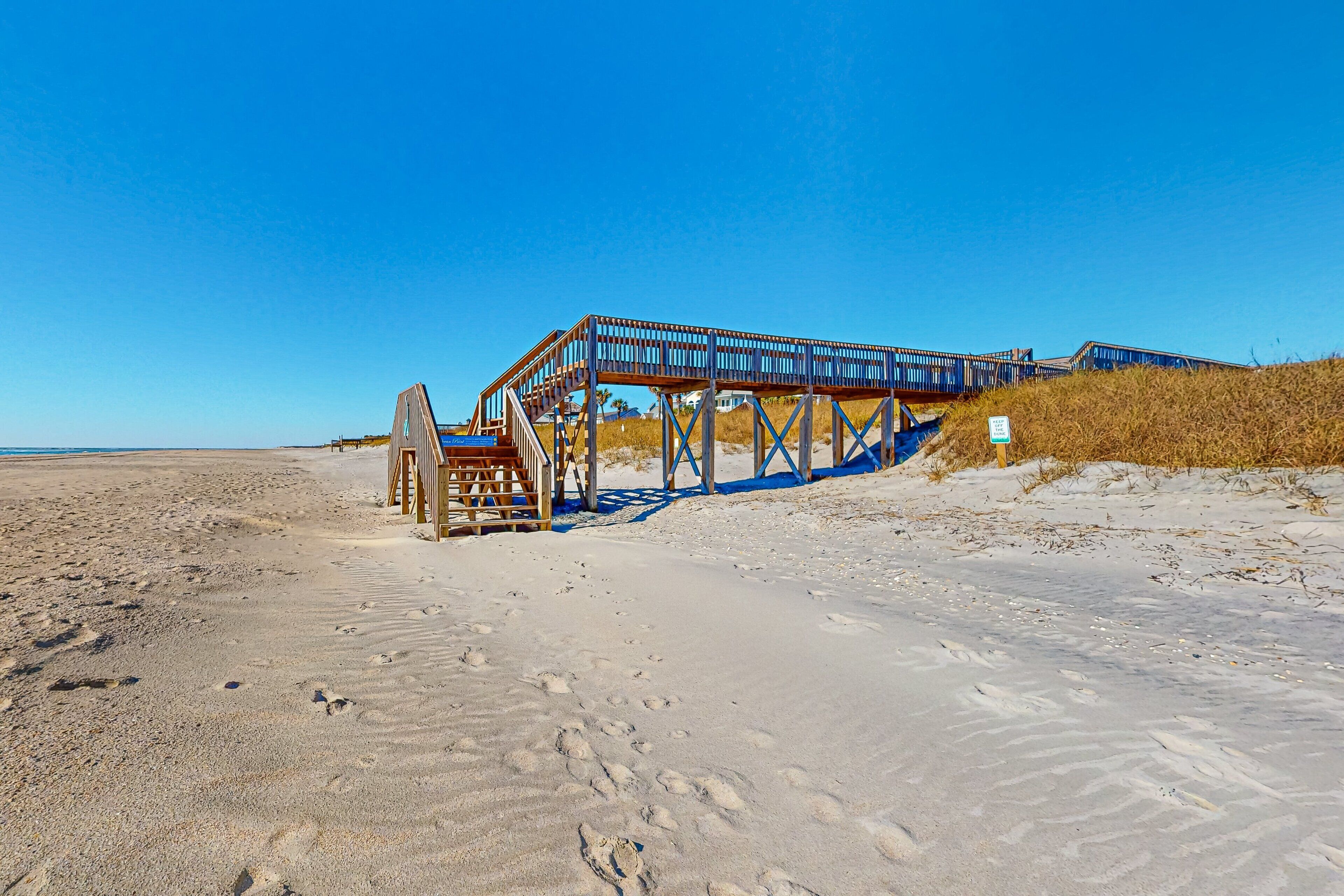 A beach with a wooden boardwalk leading to a structure with a staircase.