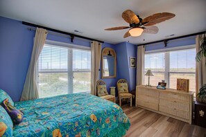 A bedroom with a bed, a ceiling fan, a dresser, and a window with curtains.