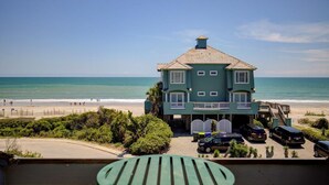 A two-story building with a balcony, a staircase leading to the upper floor, and a parking area with several cars. - Ocean View Duplex in Hampton Colony - Community Pool & Just Steps to the Beach!! (North Topsail Beach)