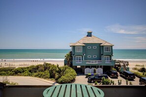 A two-story building with a balcony, a staircase leading to the upper floor, and a parking area with several cars. - Ocean View Duplex in Hampton Colony - Community Pool & Just Steps to the Beach!! (North Topsail Beach)