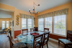 A dining area with a glass table, wooden chairs, and a chandelier.