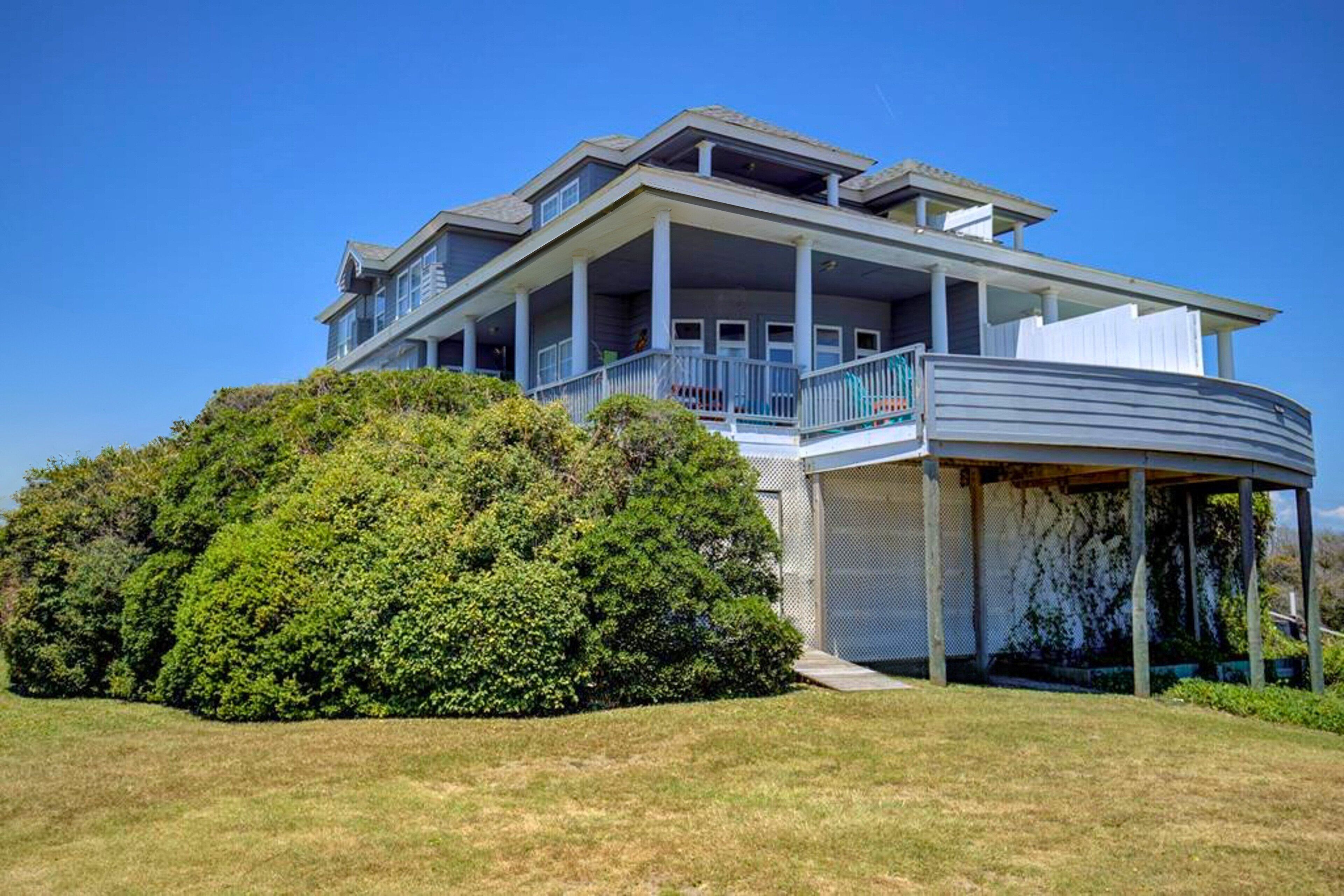 A two-story house with a large balcony, a covered porch, and a well-maintained lawn.