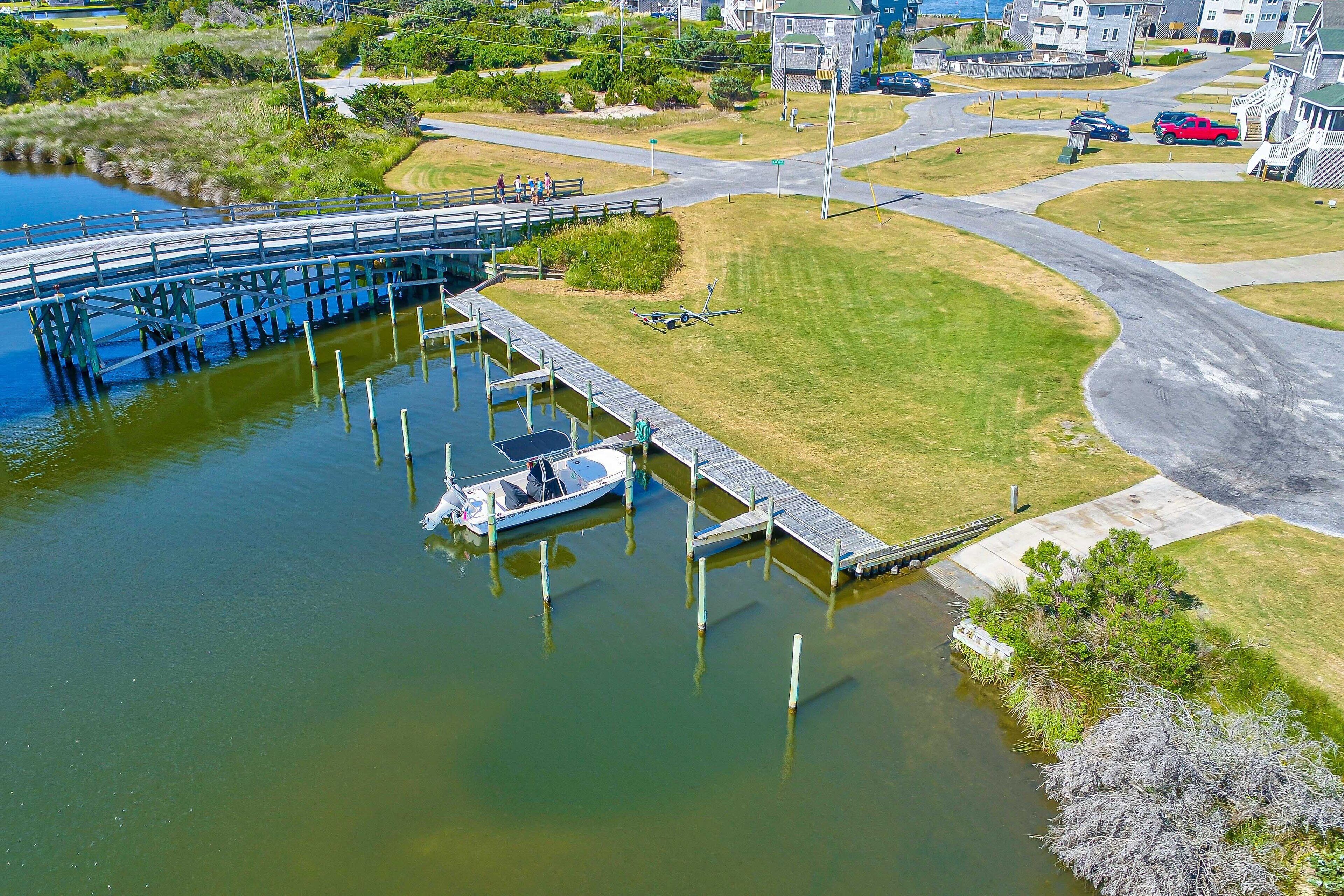 A boat docked at a pier with a grassy area and a road nearby.