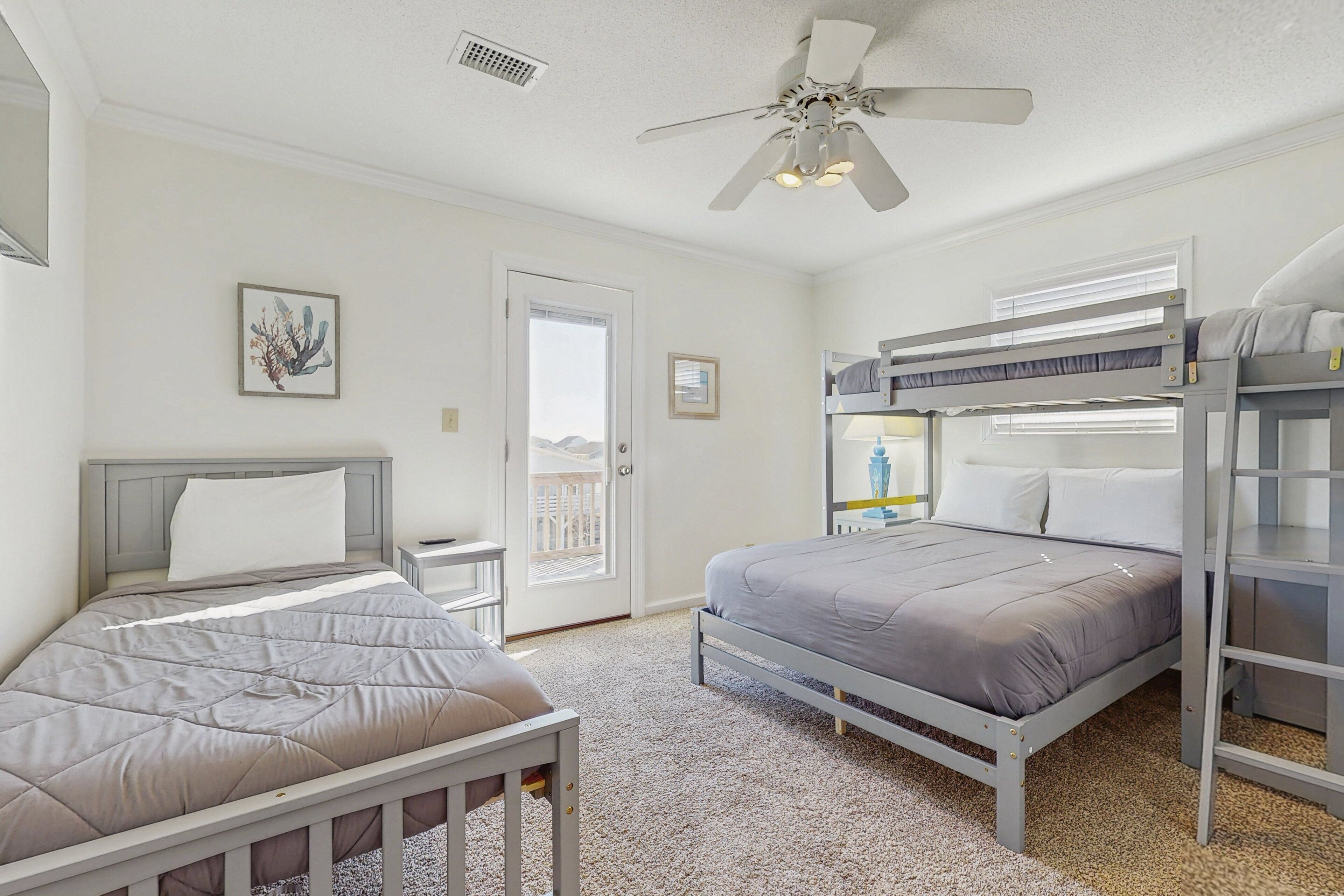 A bedroom with two beds, a ceiling fan, and a door leading to a balcony.