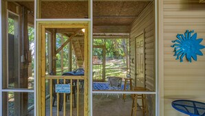 Eine überdachte Veranda mit Holzsesseln und einem Tisch, ein blauer Sessel und eine blaue Sonnendekoration an der Wand.