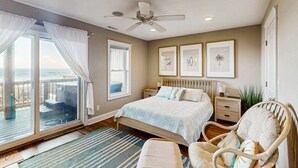 Una camera da letto con un letto, una sedia, un comodino e una ventola a soffitto.