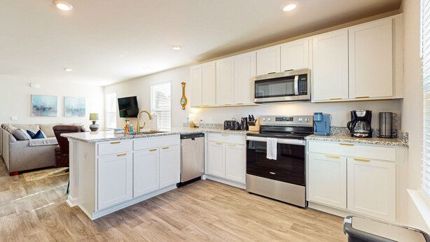 A modern kitchen with white cabinetry, stainless steel appliances, and a central island. - Salty Retreat: Fire pit | close to golf courses (Ocean Isle Beach)