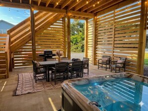 Una terrazza in legno con vasca idromassaggio, area relax esterna e una scala.