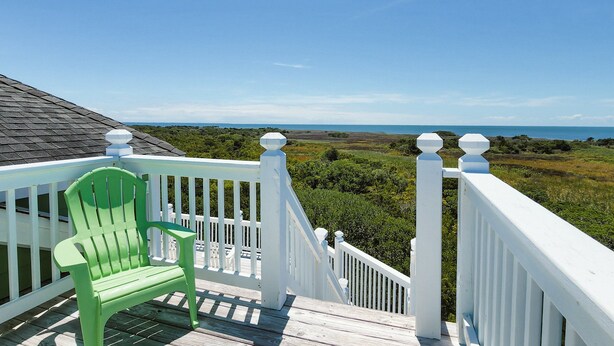 A green Adirondack chair on a white deck with a white railing, overlooking a coastal landscape with a clear sky. - Dog-friendly ocean- & sound-view home with private pool, hot tub, & central AC (Avon)