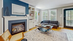 A living room with a fireplace, a sofa, a coffee table, and a bookshelf.