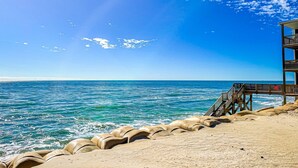 A beach with a wooden pier extending into the sea, a sandy area with tire barriers, and a clear blue sky. - Cheerful beachfront condo with balcony, tennis court, & W/D - snowbird-friendly (North Topsail Beach)