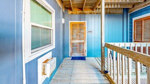 A narrow wooden corridor with a wooden railing, a door with a number, and a window with blinds. - Cheerful beachfront condo with balcony, tennis court, & W/D - snowbird-friendly (North Topsail Beach)